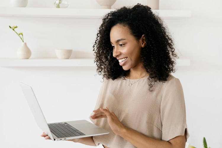 Young African American woman using laptop at home, natural light and houseplants around