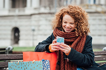 woman on phone with gift bags