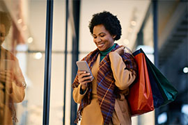 Woman on phone while holding shopping bags